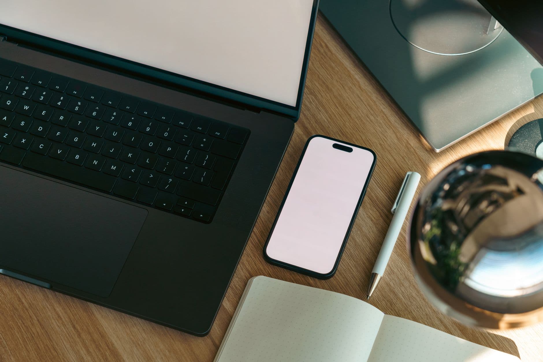 Aerial view of a modern workspace with a laptop, smartphone, and notebook showing copy space.