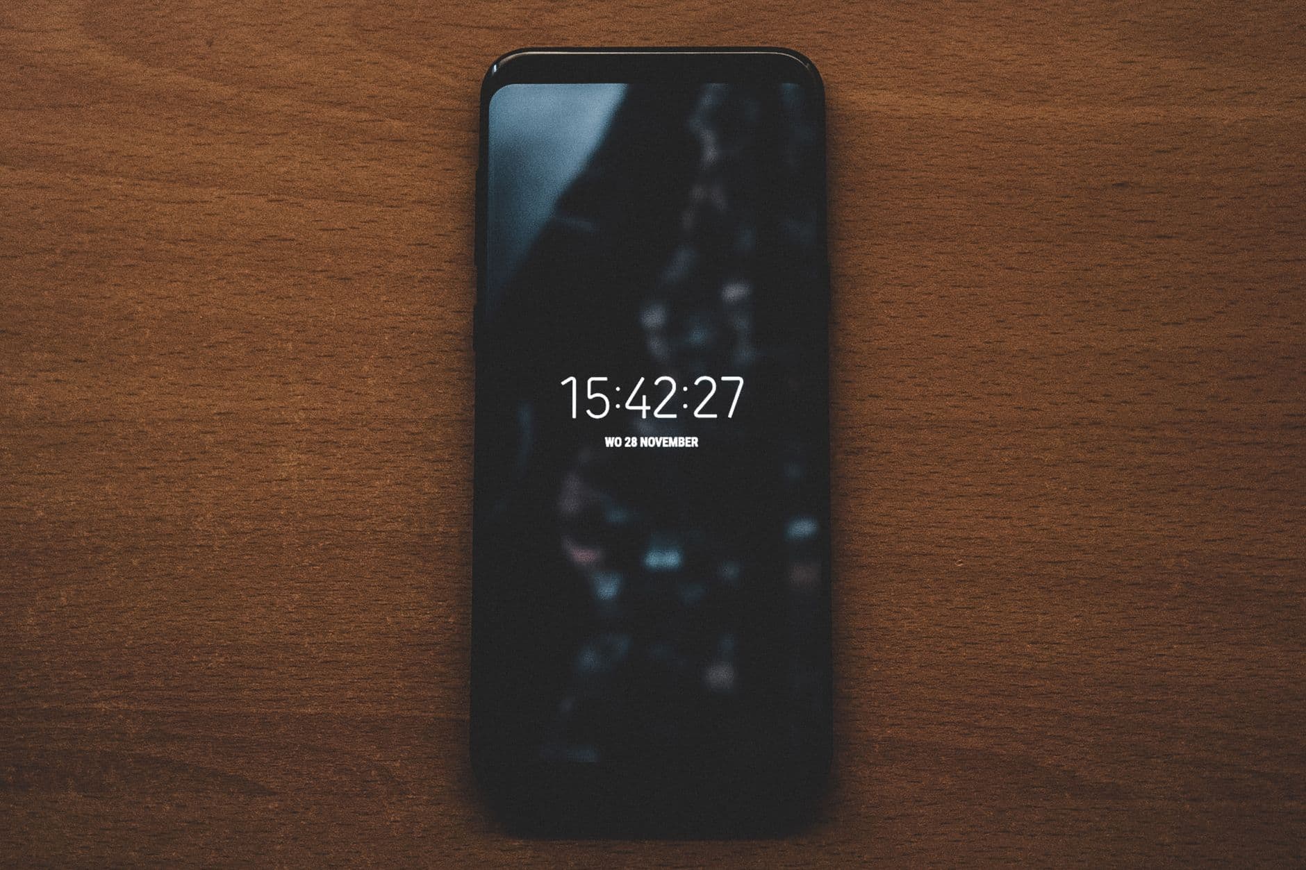 A smartphone displaying time sits on a wooden surface, showcasing modern technology.