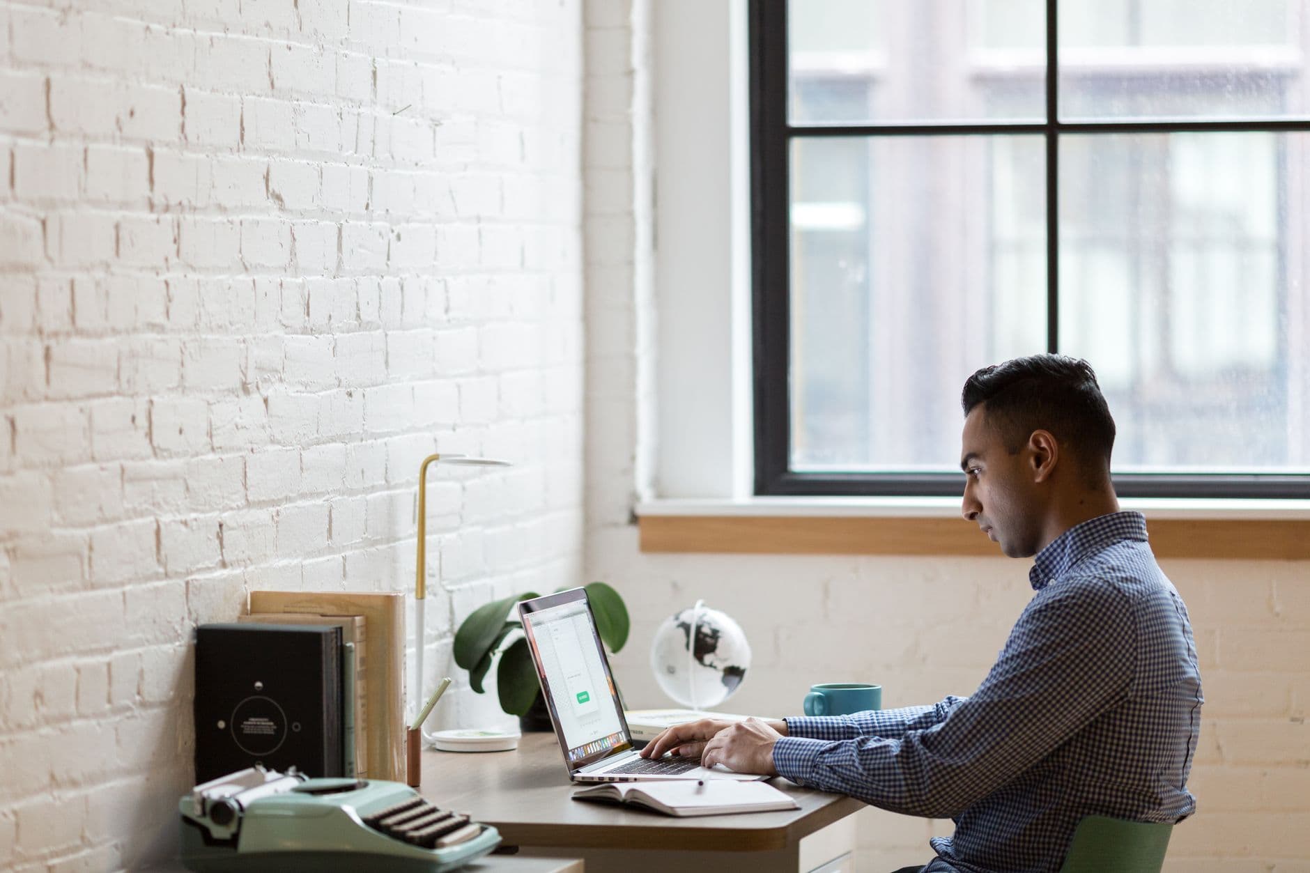 A focused businessman working on his laptop in a bright, modern office.