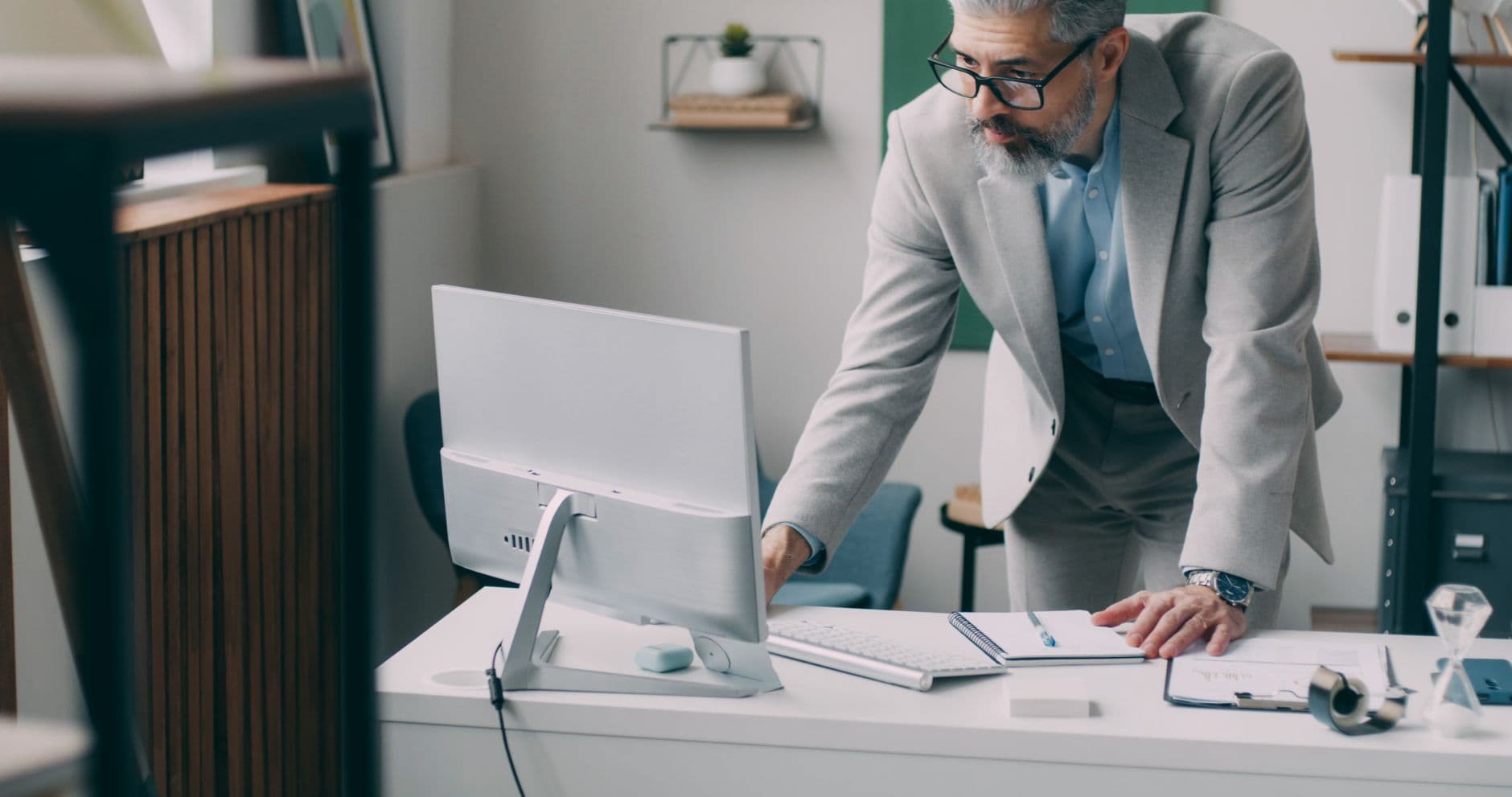 A mature businessman in a suit focusing on work at his computer in a modern office.