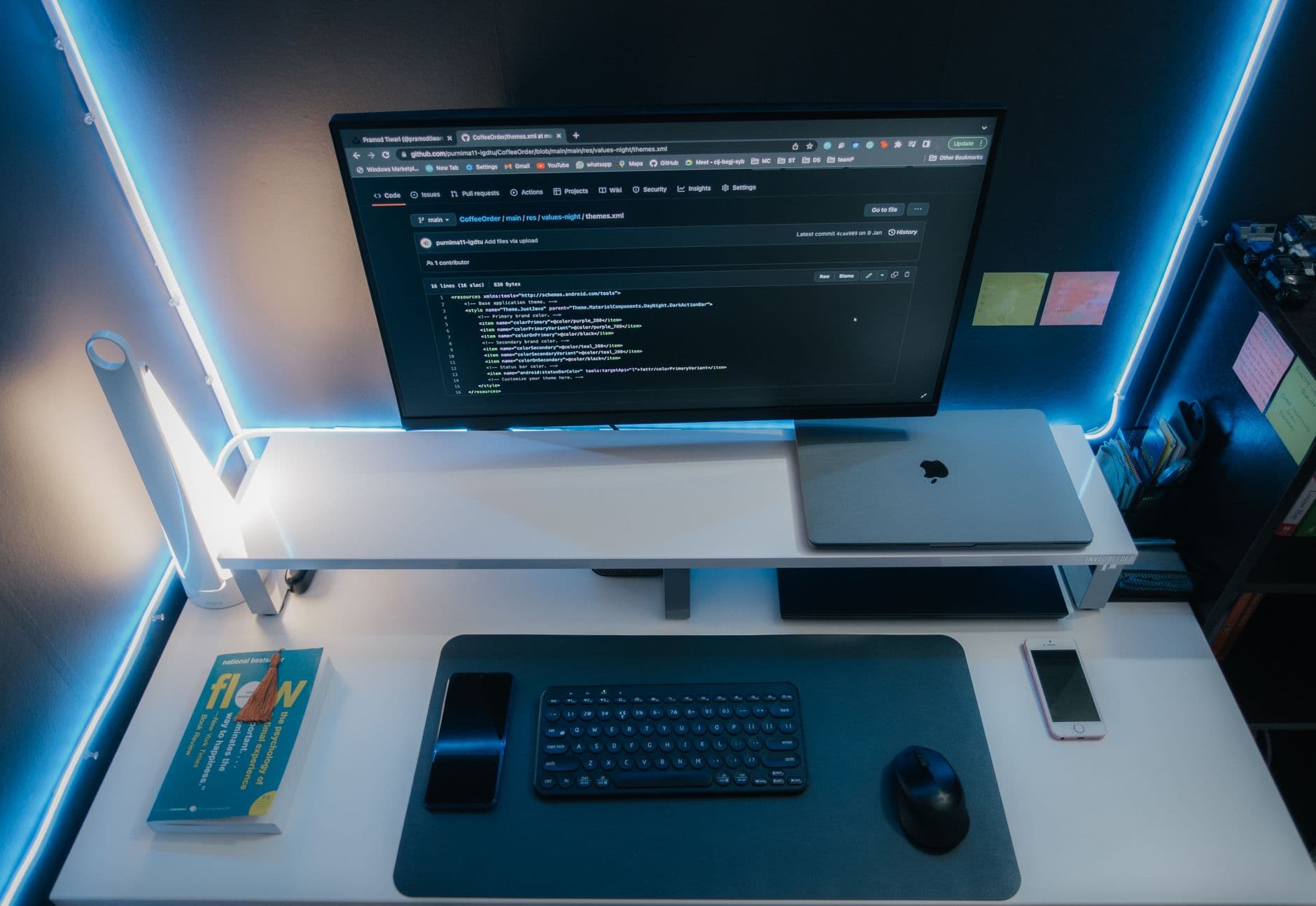 A minimalist workspace with a computer setup, gadgets, and neon lighting for a sleek modern look.