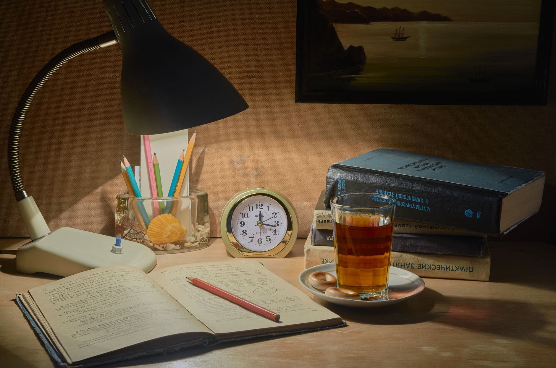 A tranquil desk setup with books, tea, and a lamp, ideal for studying.